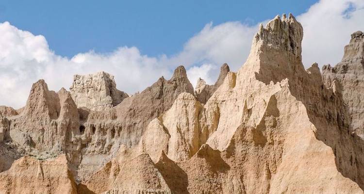 Ruwe, zandkleurige rotsformaties rijzen op tegen een blauwe hemel in Badlands-terrein.