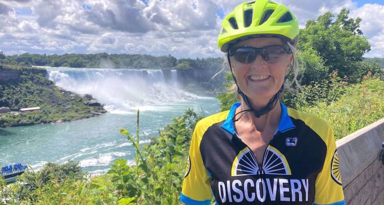 Cycliste souriant en tenue lumineuse posant avec les chutes du Niagara en arrière-plan.