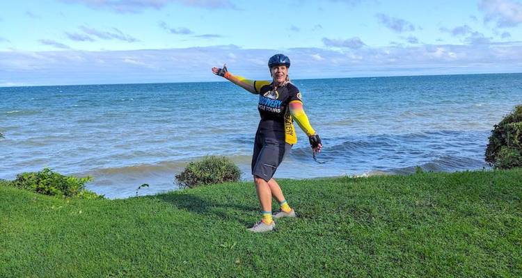 Une cycliste féminine s'étire joyeusement les bras à côté d'un rivage herbeux du lac.