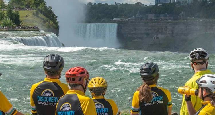 Les cyclistes vêtus de maillots assortis admirent les eaux tumultueuses des chutes du Niagara depuis un point de vue en bord de rivière.