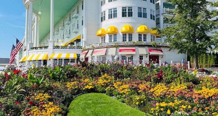 De prachtige witte gevel van het historische hotel wordt omgeven door weelderige tuinen met kleurige bloemen.