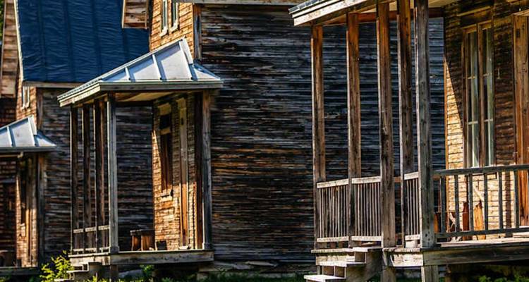 Rangée de cabanes rustiques en bois avec des vérandas ensoleillées et un revêtement usé par les intempéries