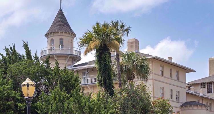 Historisch strandhuis gedeeltelijk verborgen door palmbomen en groene planten
