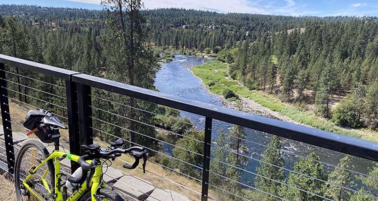Vélo de montagne appuyé contre une barrière avec vue sur une rivière forestière aux eaux rapides