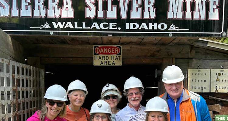 Un groupe de touristes souriants portant des casques de sécurité pose à l'entrée de la Sierra Silver Mine à Wallace, Idaho.