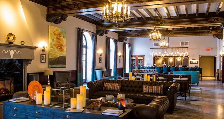 Hall d'entrée élégant d'un hôtel historique avec canapés en cuir, lustres et bougies décoratives.