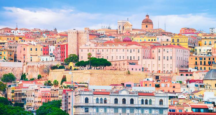 Los edificios de colores pastel, las murallas medievales y una catedral con cúpula dominan el horizonte de Cagliari en un día despejado.