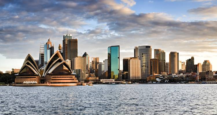 Klassische Seitenansicht der Segel des Sydney Opera House mit modernen Wolkenkratzern und ruhigen Hafengewässern