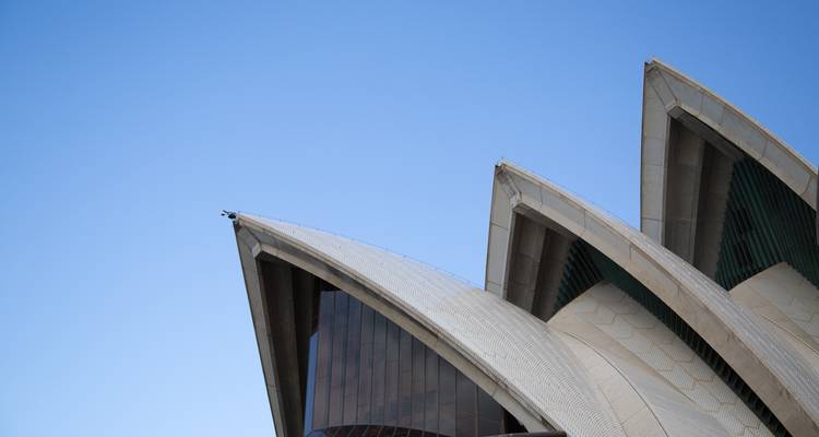 Gros plan minimaliste de trois voiles en béton blanc de l'Opéra de Sydney contrastant avec un ciel bleu dégagé