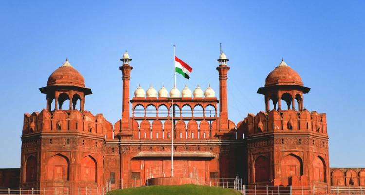 Ikonische rote Sandsteinfestung Red Fort mit indischer Trikolore, die unter klarem blauen Himmel weht.