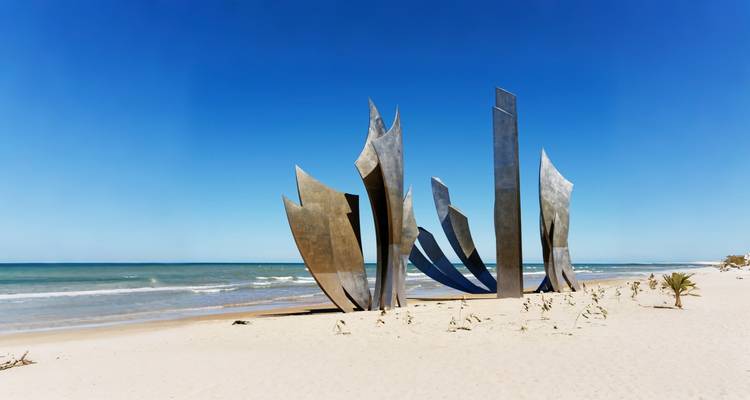La sculpture commémorative « Les Braves » en acier inoxydable s'élève depuis la large plage de sable d'Omaha Beach.