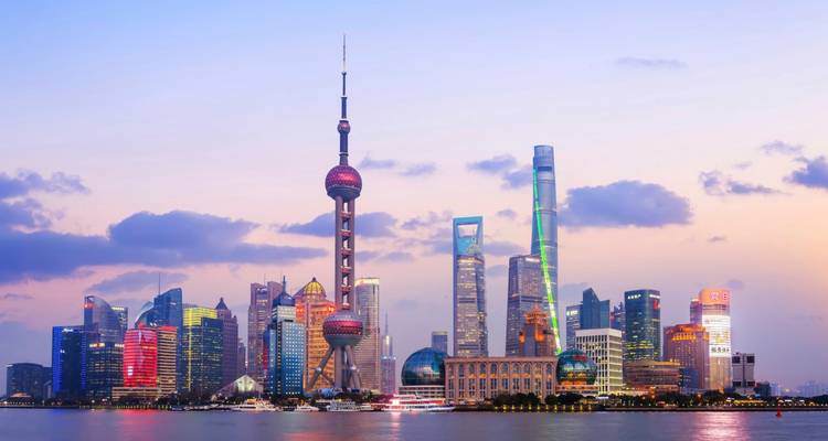 El futurista skyline de Shanghái brilla al atardecer, dominado por la Perla Oriental y los rascacielos que se elevan reflejados en el río Huangpu.