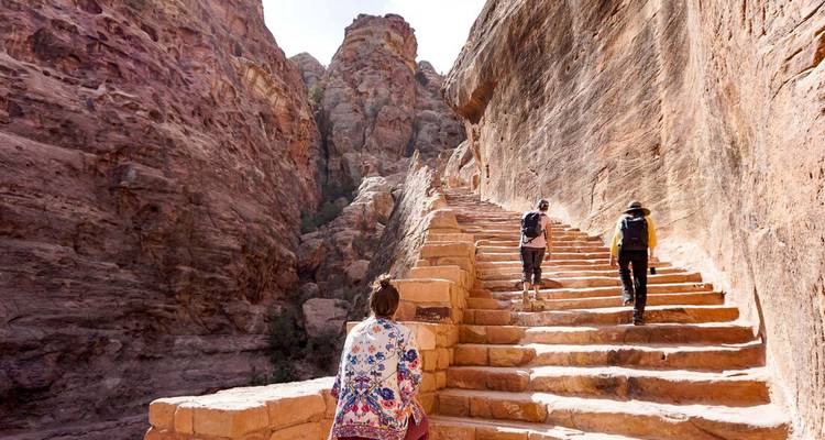 Les randonneurs gravissent les anciens escaliers en grès entre les parois rocheuses imposantes de Pétra