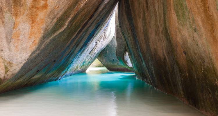 El agua turquesa iluminada por el sol fluye a través de un estrecho pasaje entre rocas de granito en los Baños de Virgin Gorda.