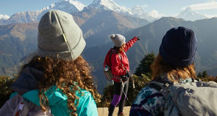 Les randonneurs font une pause à un point de vue tandis que l'un d'eux pointe du doigt vers la chaîne enneigée de l'Annapurna