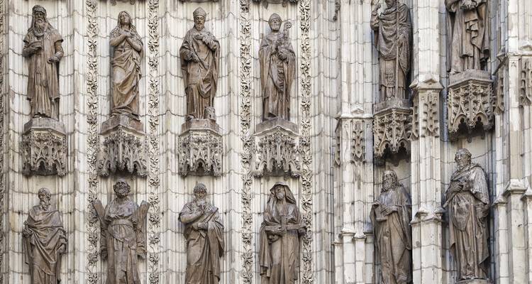 Steinstatuen, die eine gotische Kathedralenfassade mit detaillierten Säulen schmücken.