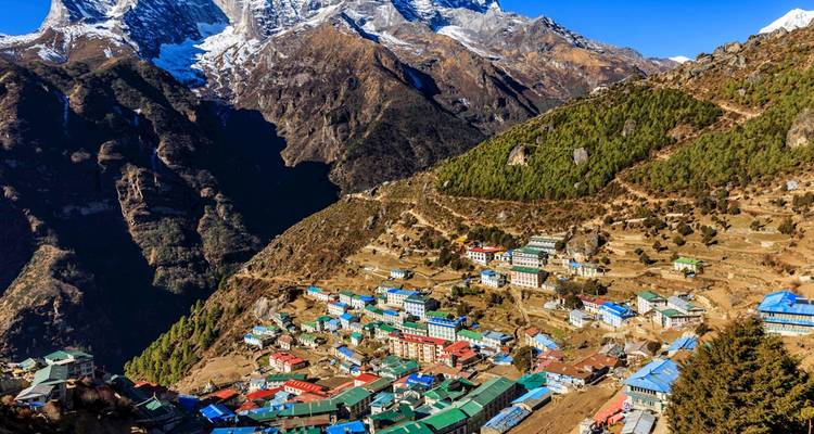 Colorido pueblo en terrazas de Namche Bazaar acurrucado bajo las dramáticas crestas del Himalaya y picos nevados.