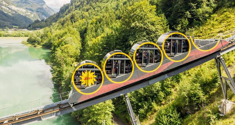 Funicular moderno de inclinación con vagones de ventanas circulares ascendiendo una pendiente boscosa empinada junto a un lago río turquesa.