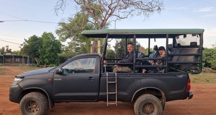 Camión de safari al aire libre estacionado con viajeros listos para una excursión de vida silvestre en un camino polvoriento.