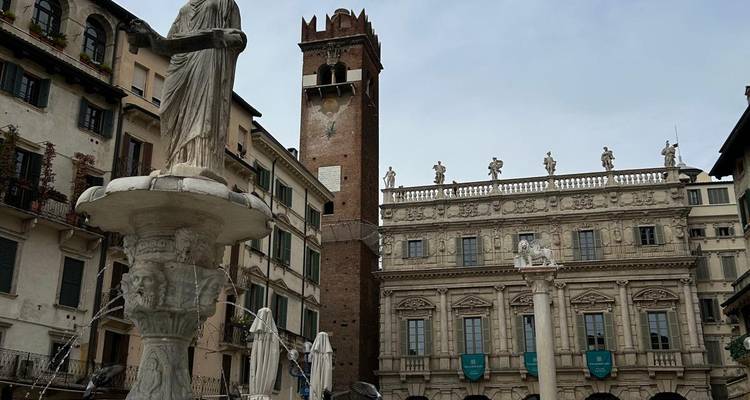 Fontaine avec statue et tour médiévale dominant la Piazza delle Erbe de Vérone.