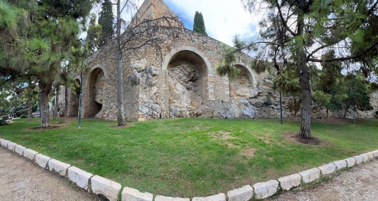 Les murs de fortification en pierre et les arches bordés de pins dans une zone de parc tranquille.