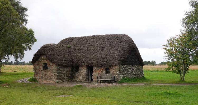 Cabaña de piedra con techo de paja ubicada en los campos verdes del Campo de Batalla de Culloden.