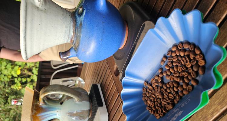Exhibición de mesa con granos de café tostados junto a vasijas de cerámica para preparar café durante una sesión de degustación.