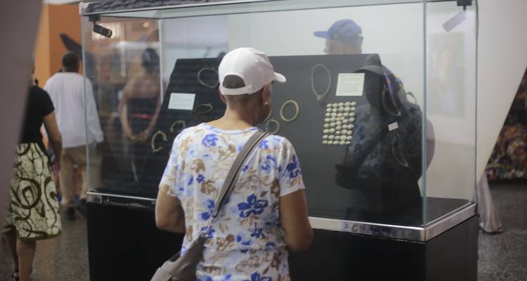 A museum visitor studies gold jewellery displays in a glass case.