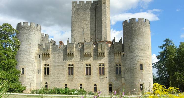 Massief stenen fort met een hoge centrale donjon en cilindervormige hoektorens die tegen de gebroken wolken uitsteken.