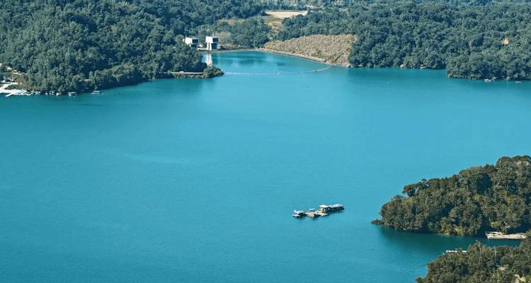 Luftaufnahme des glänzend blauen Sees Sun Moon Lake, umgeben von üppigen bewaldeten Hügeln.
