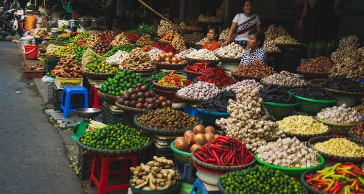 Levendige straatmarkt met stapels kleurrijke fruit, groenten en kruiden netjes in manden gerangschikt.