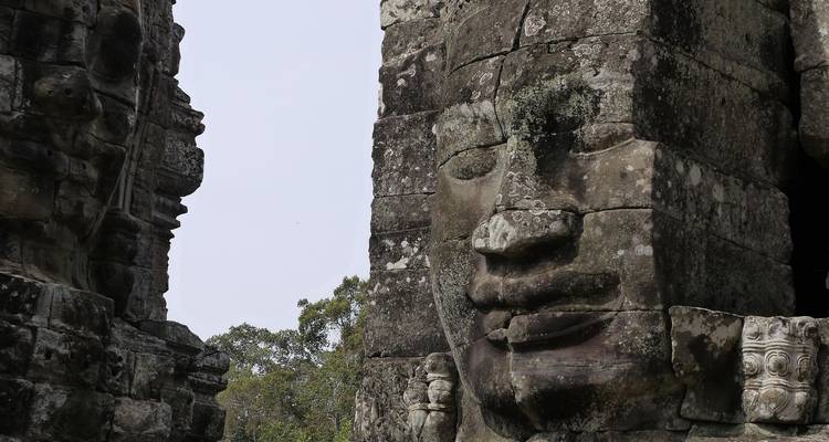 Nahaufnahme eines Steinprofils eines Gesichts des Bayon-Tempels, umrahmt von verwitterten Blöcken.