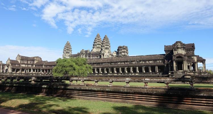 Vollständige Fassade von Angkor Wat unter einem strahlend blauen Himmel, umrahmt von grünem Rasen.