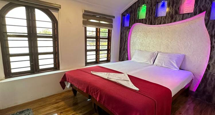 Kompaktes Schlafzimmer mit roter Bettdecke, Stimmungslicht in farbigen Nischen und Holzbodenbelag auf einem Boot.