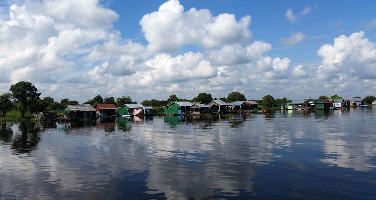 Häuser des Schwimmenden Dorfes spiegeln sich in ruhigen Seewassern unter verstreuten Wolken.