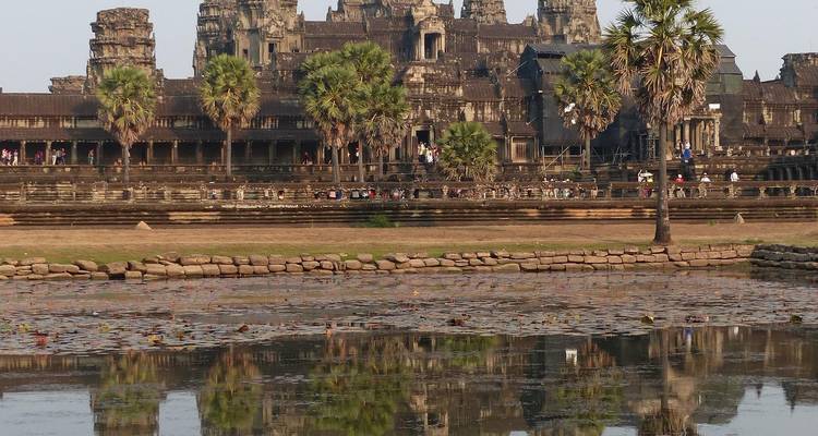 Ikonische Türme von Angkor Wat spiegeln sich im Tempelteich wider, mit Besuchern im Hintergrund.