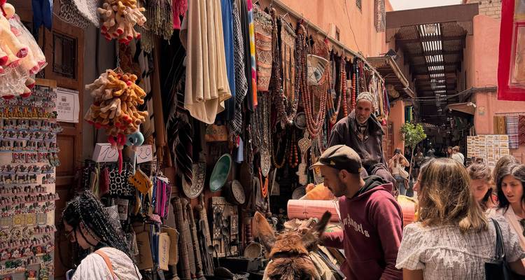Bullicioso zoco en Marrakesh lleno de puestos con cuentas coloridas, alfombras y visitantes navegando por callejones estrechos.