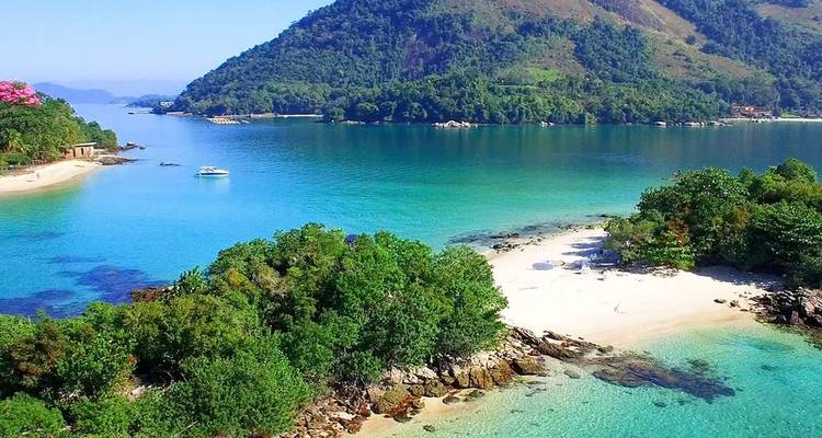 Petite anse tranquille avec plage blanche, feuillage verdoyant et eau turquoise cristalline