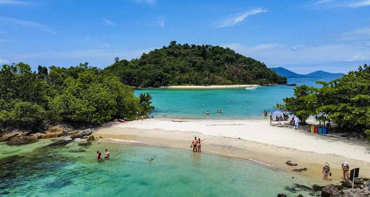 Playa de banco de arena entre dos islas exuberantes con visitantes vadiendo en una laguna de agua turquesa poco profunda