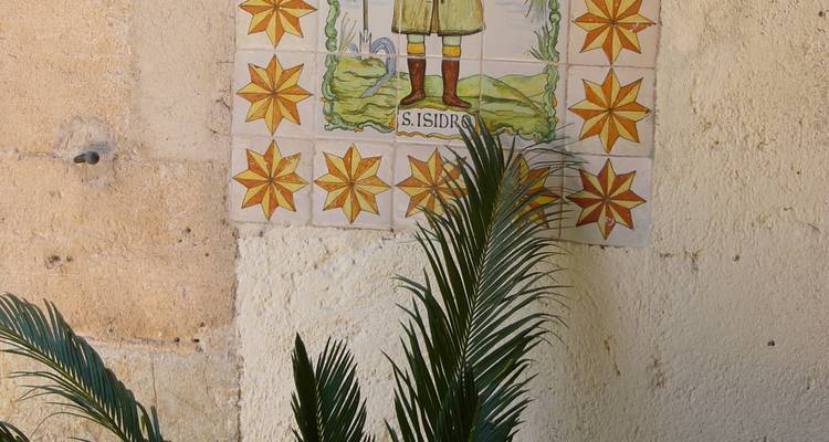 Handbemaltes Keramikfliesenmosaik, das den heiligen Isidro mit geometrischen Stermotiven auf einer Stuckwand darstellt.