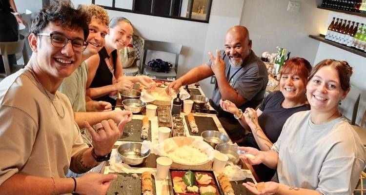 Smiling travelers around a table rolling sushi during a cooking class