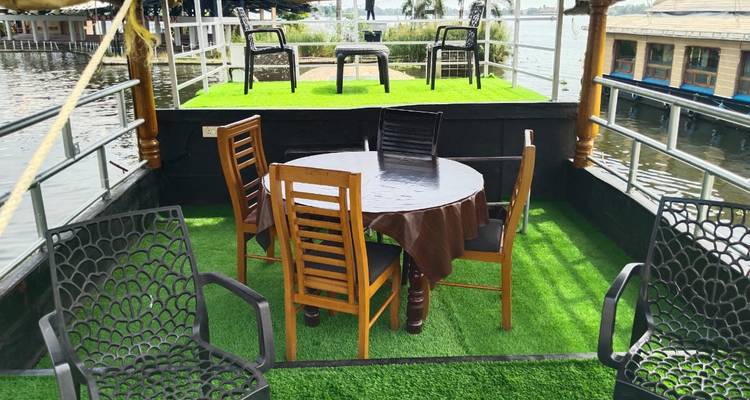 Oberdeck eines Hausboots mit Kunstrasen, Holztisch und Stühlen mit Blick auf ruhige Backwaters.