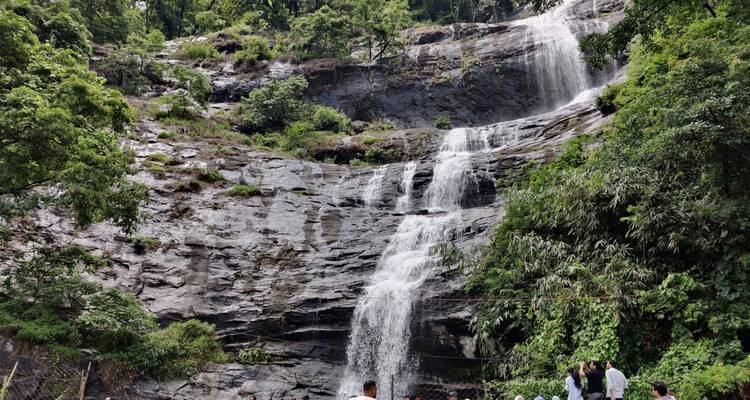 Besucher versammelten sich am Fuße eines stufenförmigen Wasserfalls, der von üppiger Vegetation umgeben ist