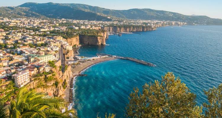 Panoramisch uitzicht over Sorrento's gebogen strand en grillige kustlijn met glitterend blauwe zee.