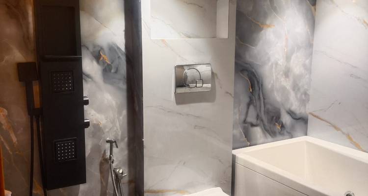 Badezimmer mit Marmorfinish, Badewanne und wandhängende Toilette mit eleganter Beleuchtung