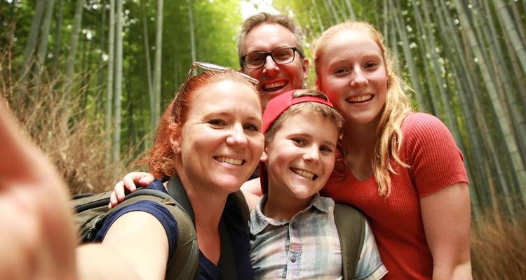 Family selfie amid towering bamboo stalks in a lush forest setting.