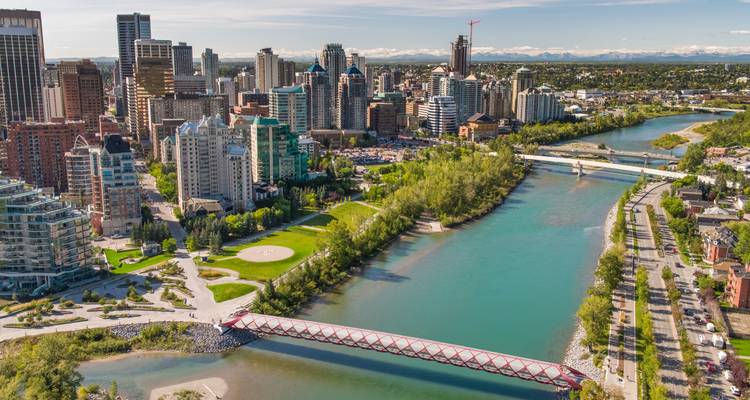 Aerial view of Calgary skyline, Bow River and red pedestrian Peace Bridge on a sunny day.