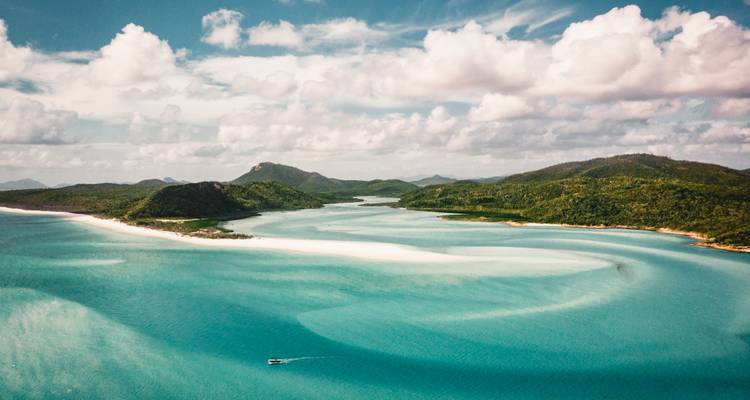 Vue aérienne des baies turquoise éclatantes et des bancs de sable aux Whitsundays sous des nuages cotonneux