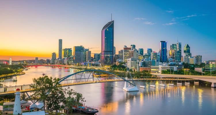 Skyline moderne de Brisbane brillant à la lumière du soir au-dessus de la Brisbane River sinueuse avec ses ponts et ses reflets.