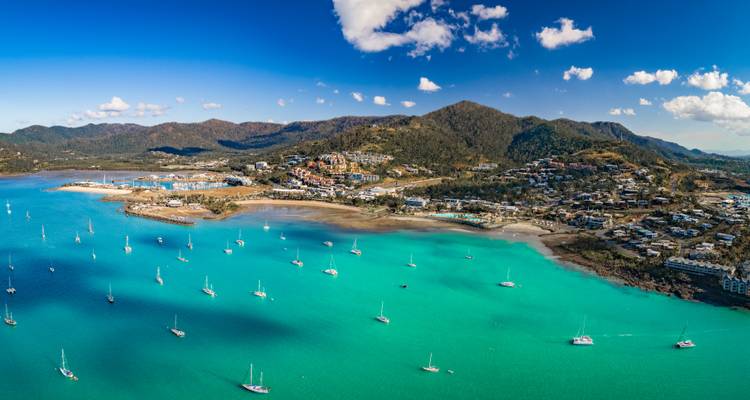 Vue aérienne des baies turquoise et des yachts mouillés à côté des collines verdoyantes d'Airlie Beach.